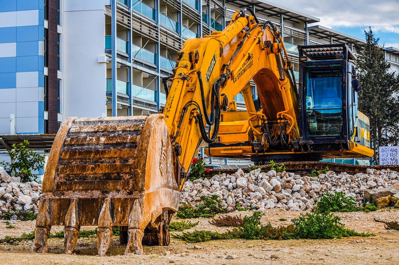 An excavator with a large material bucket touching the ground