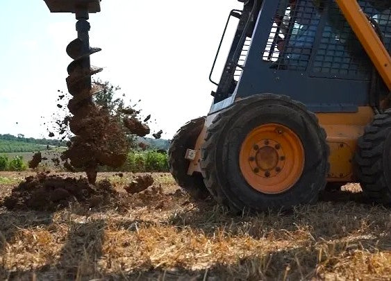 a yellow skid steer with an auger attachment